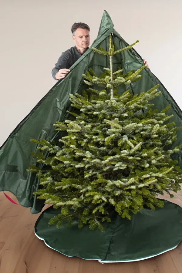 Mann verpackt Tannenbaum mit TreeButler® Weihnachtsbaumhülle